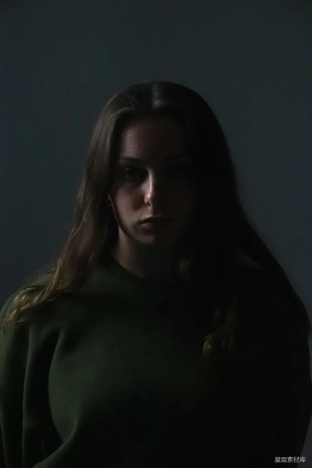 高清摄影  一个穿着绿色毛衣的女人在一间黑暗的房间里