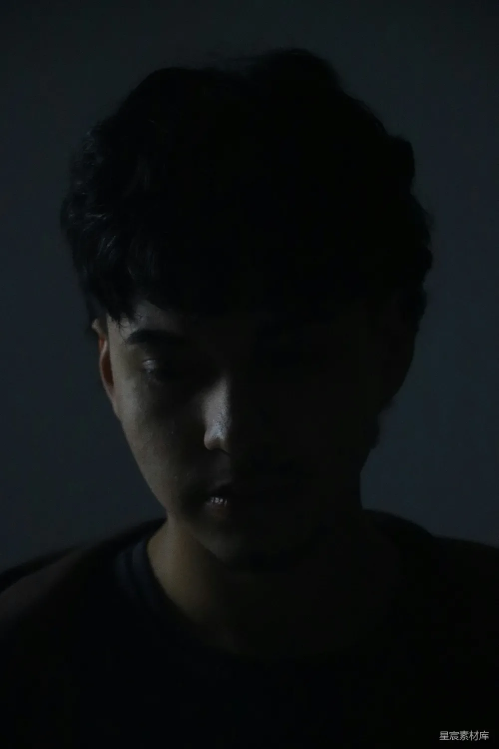 高清摄影 一个男子身处黑暗的房间里，眼睛闭上。