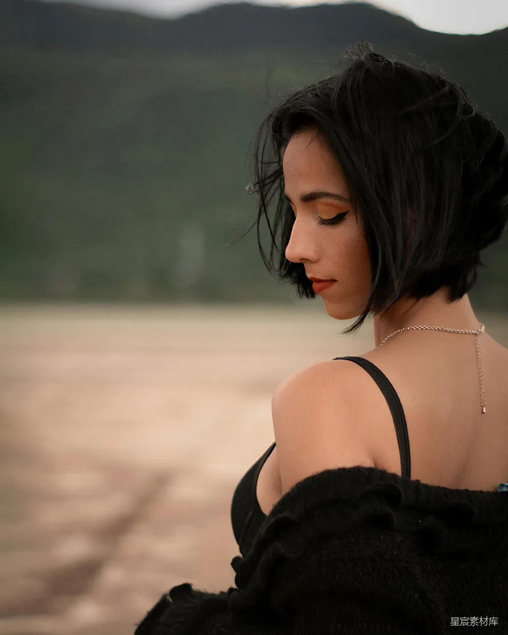 高清摄影 一个穿着黑色连衣裙的女人低头看着她的手机。