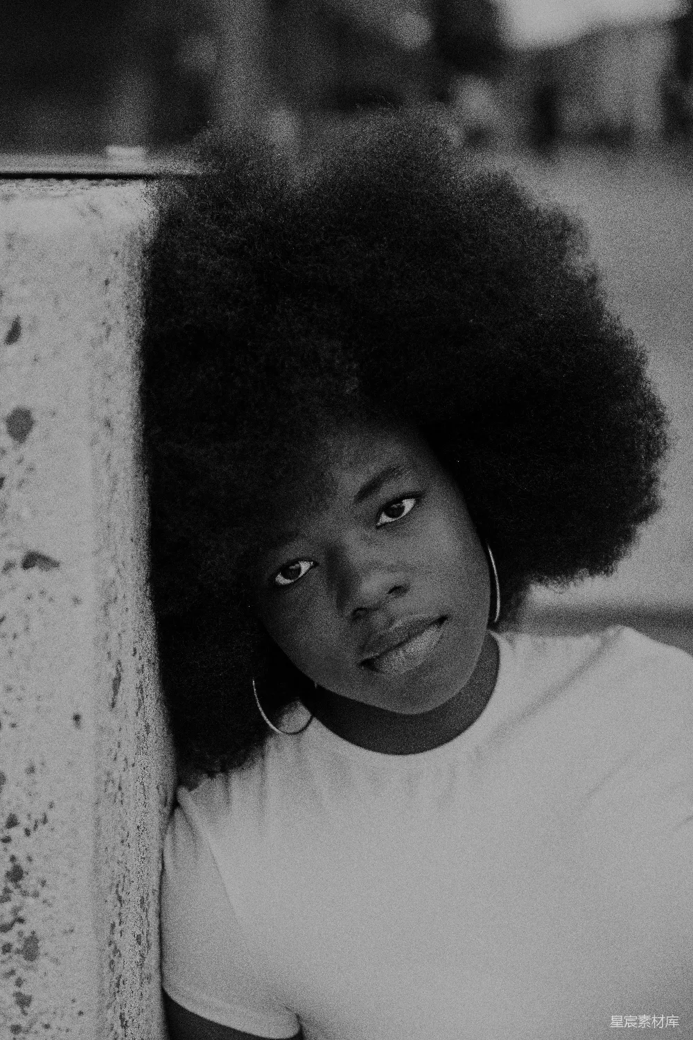 高清摄影 一个留着 Afro 的妇女靠在墙上。