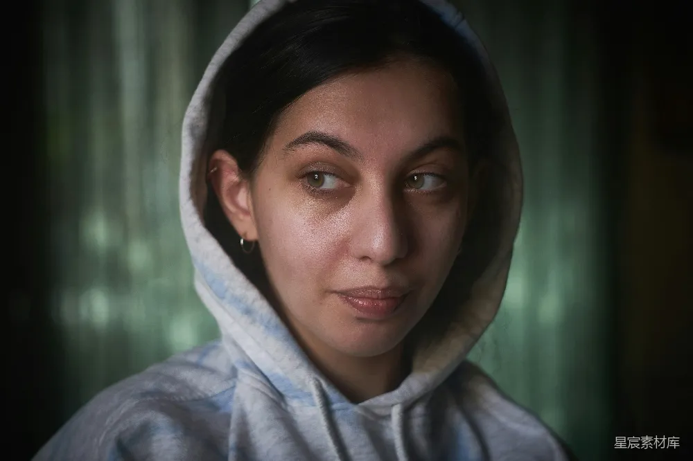 高清摄影  一个穿着连帽卫衣的女人正在看着镜头。