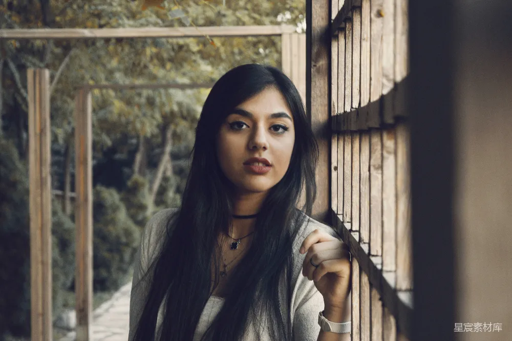 高清摄影 一个女人站在一块木墙旁边。