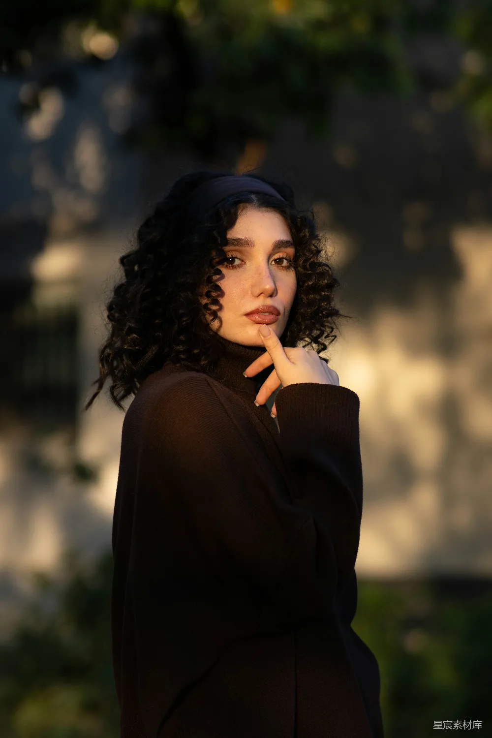 高清摄影  一个留着 curly 头发的女性穿着一件深色的圆领毛衣。