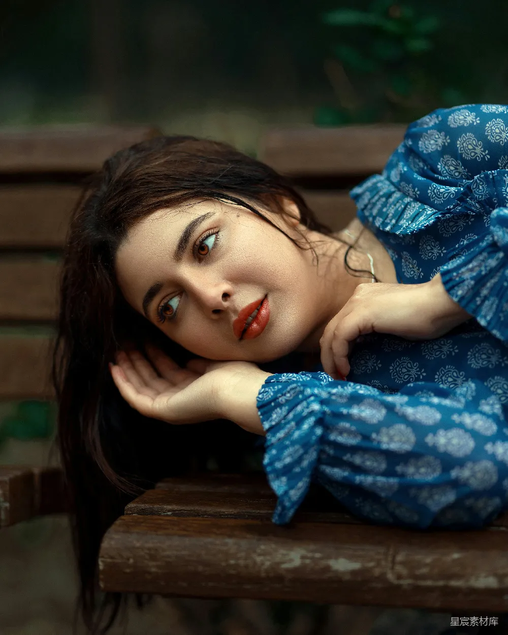 高清摄影  一个穿着蓝色衣服的女人躺在木制长凳上。