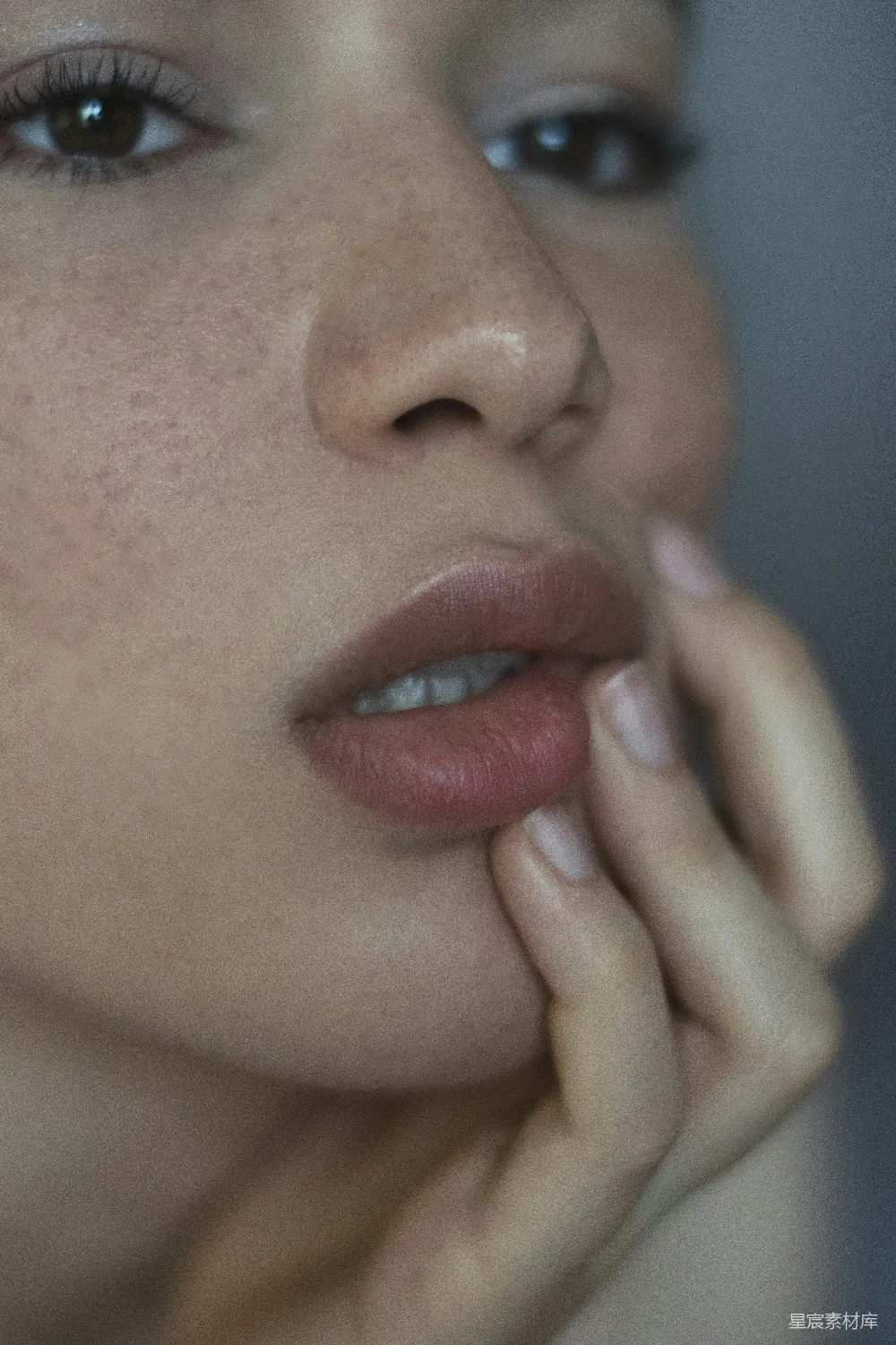 高清摄影 一个带着雀斑的女人，手放在嘴唇上。