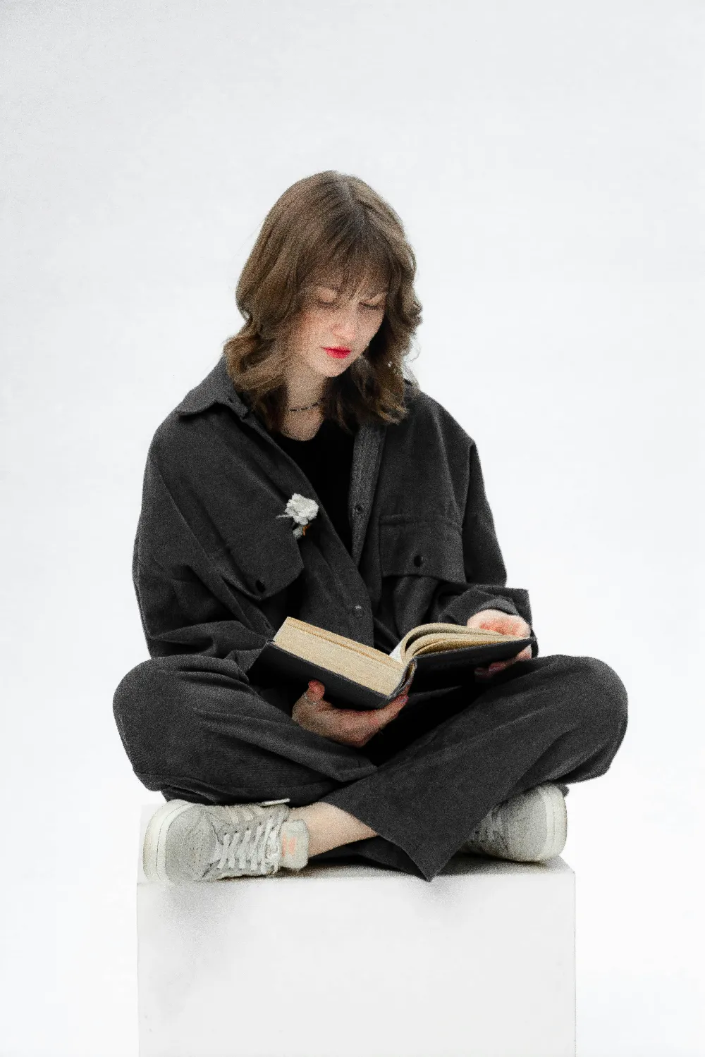 高清摄影 一个女人坐在一个立方体上阅读一本书