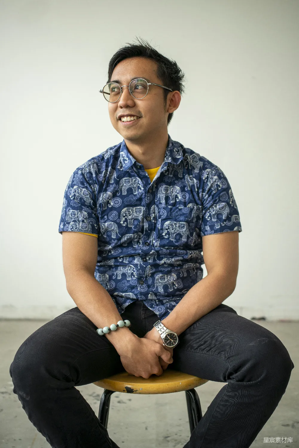 高清摄影 笑眯眯的男人坐在凳子上，侧头望着。