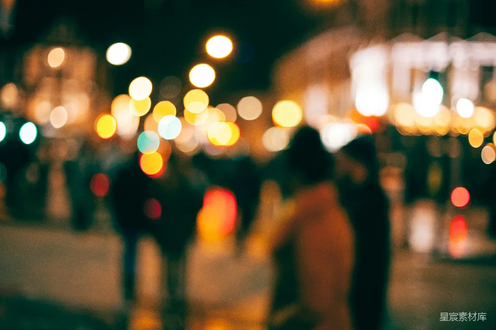 高清摄影 一个模糊的夜景中人们在小镇上行走的画面，周围是散乱的光斑。