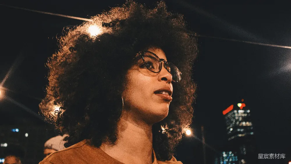 高清摄影 夜间专注于身穿棕色圆领上衣并佩戴黑色框架眼镜的女性的摄影