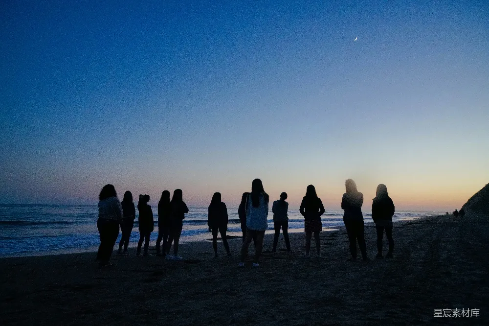 高清摄影 海边的人们在夜间站立。
