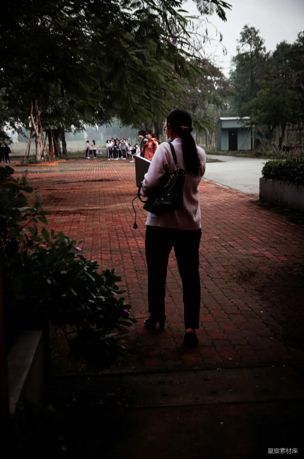 高清摄影 一个女人站在砖砌的小径上，正在打电话。