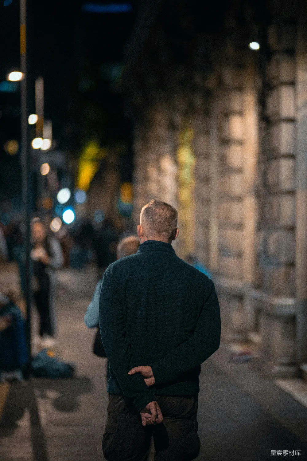高清摄影 一个男人站在夜间的 sidewalk 上