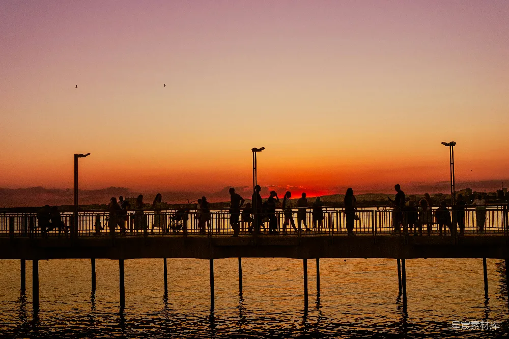 高清摄影 人们在夕阳绚烂的海堤上行走。