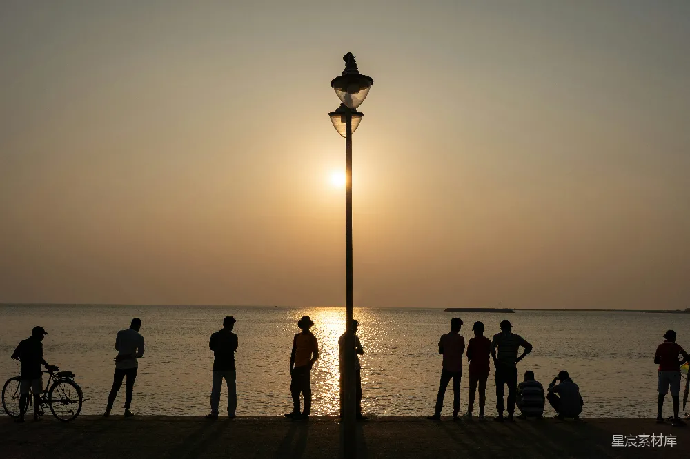 高清摄影  夕阳下水面上轮廓分明的人和路灯。
