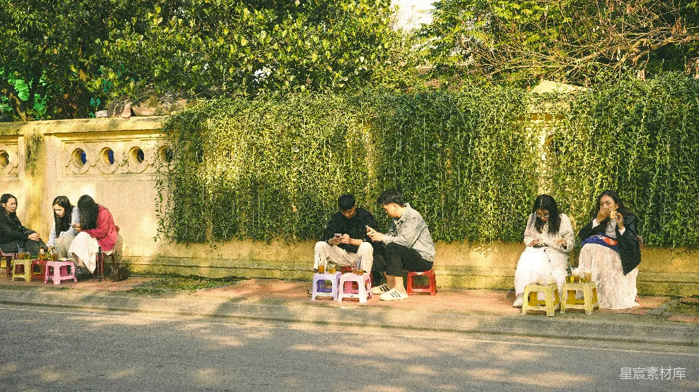 高清摄影 坐在小凳子上的人们聚集在一条小巷里。