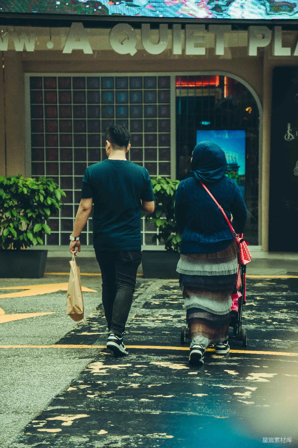 高清摄影  一对夫妇带着《一个安静的地方》走向一家商店。