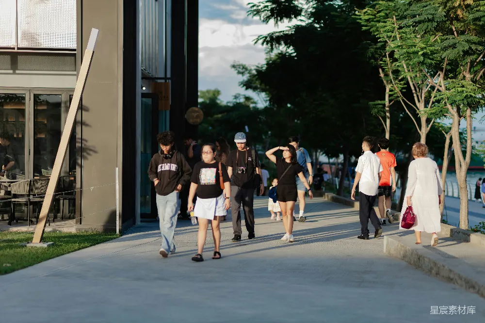 高清摄影 人们走在阳光下的 sunny waterfront promenade 上。