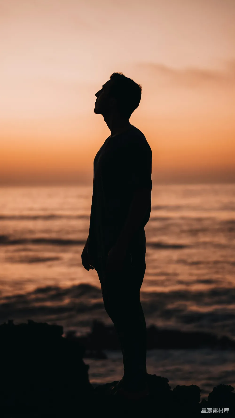 高清摄影 一个男人站在海边的山顶上，旁边是海洋。