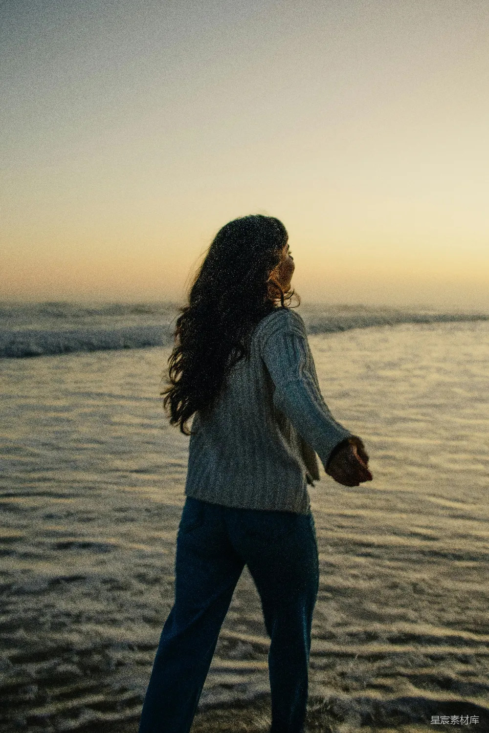 高清摄影 女人站在海灘上，夕阳西下。