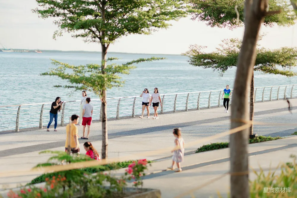 高清摄影 人们在傍晚时分走在 waterfront promenade 上。