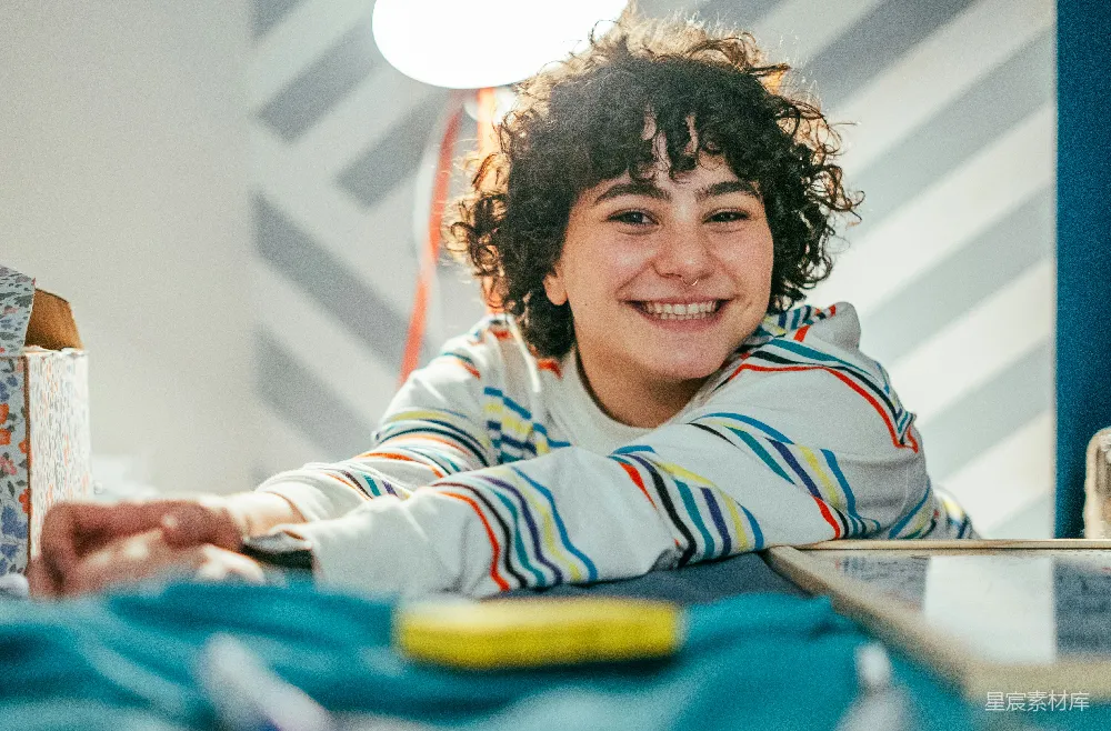 高清摄影  一个年轻男孩坐在桌子旁笑着。