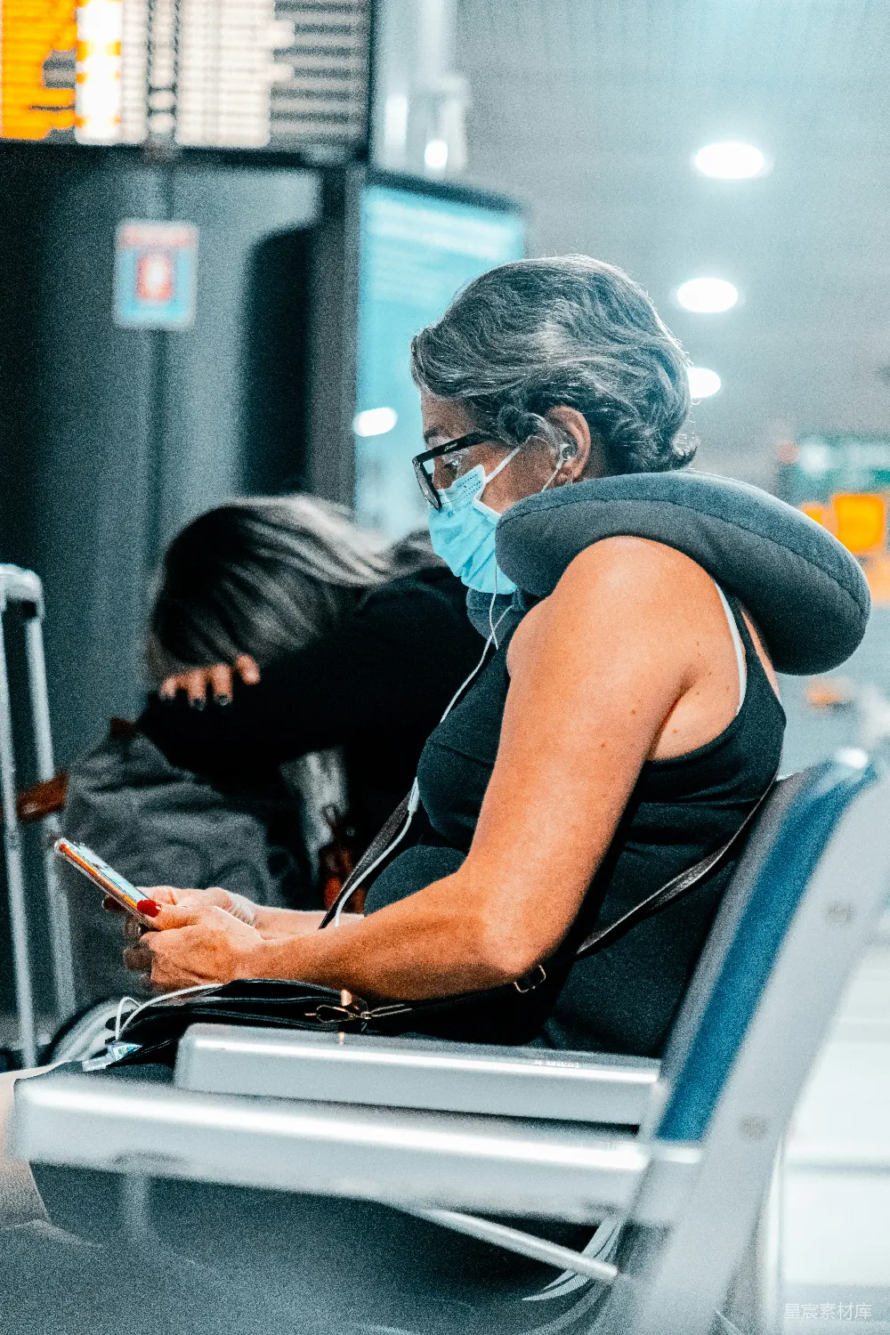 高清摄影 蓝色T恤的女人戴着白色的耳机，手持智能手机。