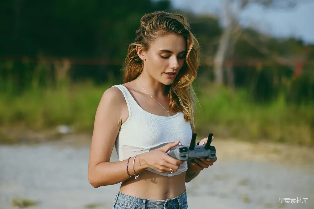 高清摄影 海滩上站着一位妇女拿着相机。