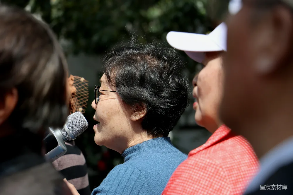 高清摄影 一个妇女手持麦克风站在一群人面前