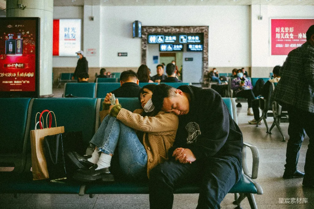 高清摄影 机场里，一名男性和一名女性坐在长凳上。