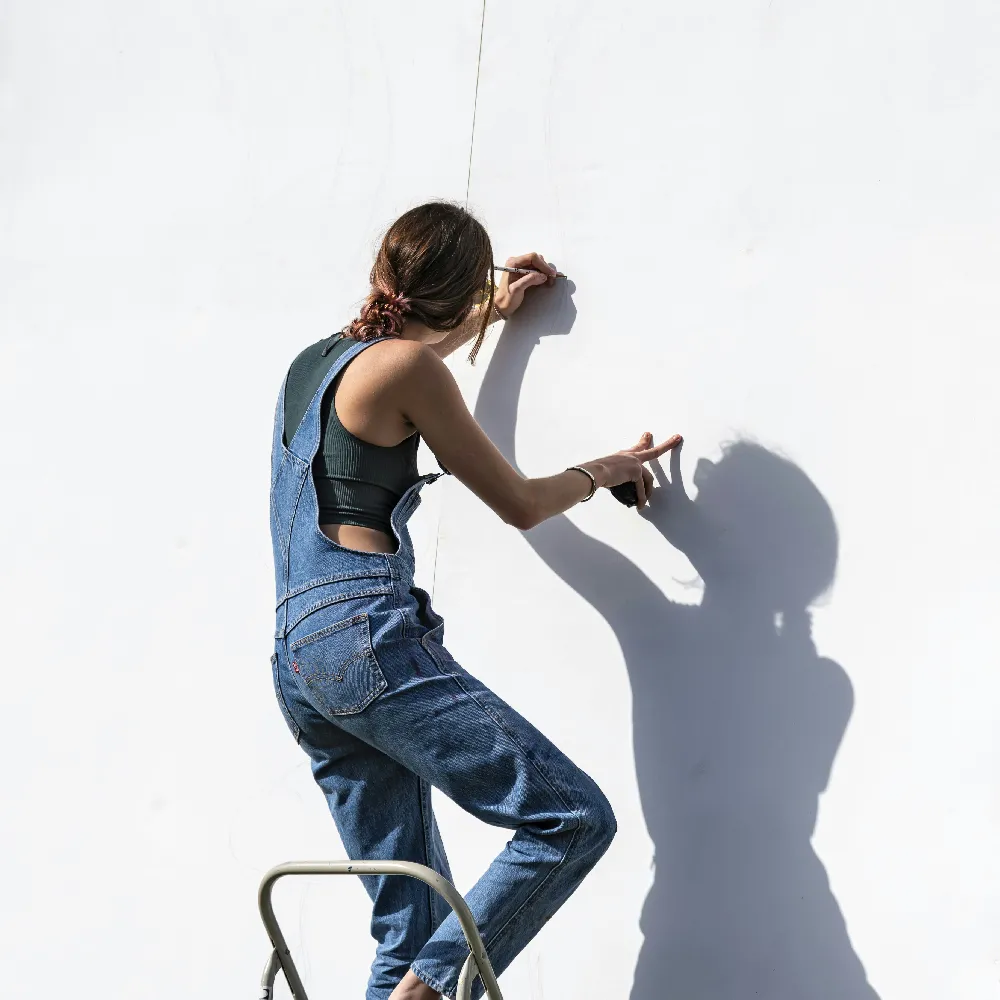 高清摄影 身穿蓝 denim 牛仔裤和黑色紧身 T 恤的女人坐在椅子上。