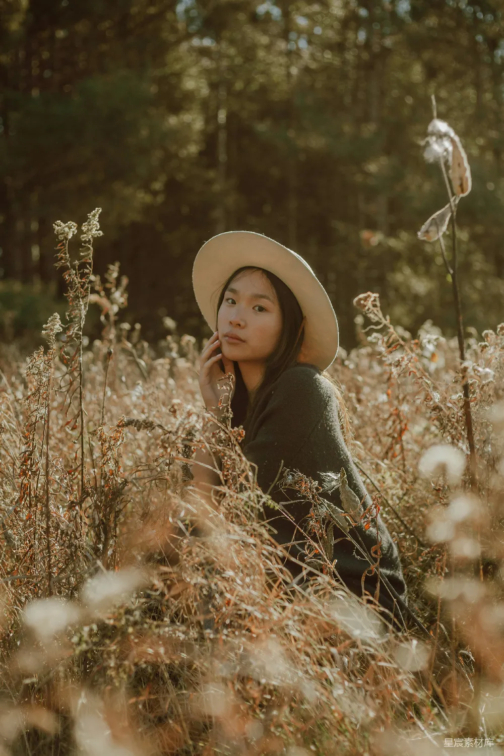 高清摄影 黑色长袖上衣的女人戴着浅褐色的太阳帽站在褐色的草地上。