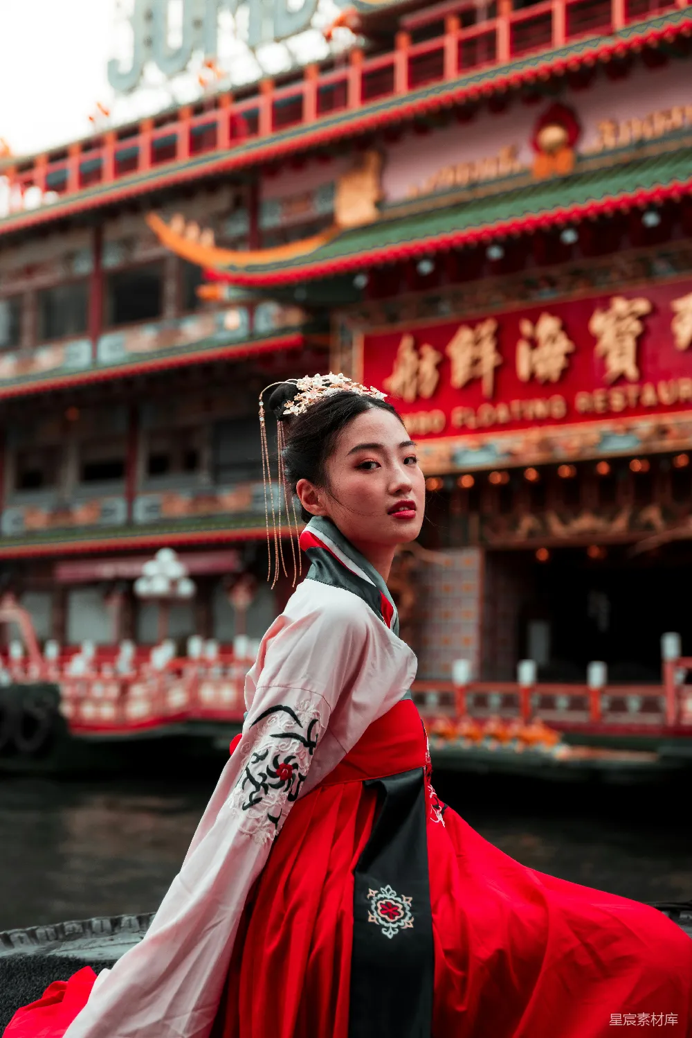 高清摄影 一个穿着红黑相间连衣裙的女人站在建筑物前。
