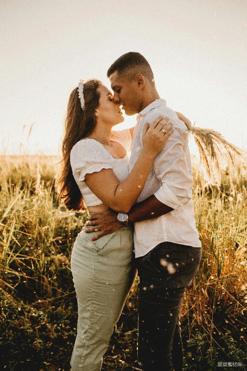 高清摄影 人物 男人在白天的草地上亲吻女子的前额，地点是在褐色的草地上方。
