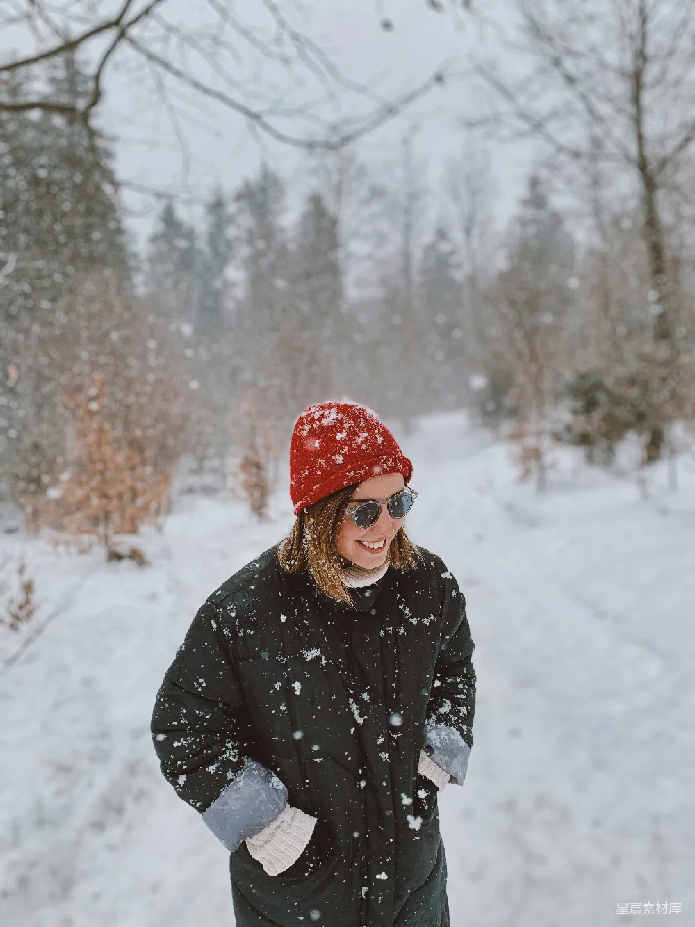高清摄影 人物 一个女人站在雪地里，戴着一顶红色的帽子。