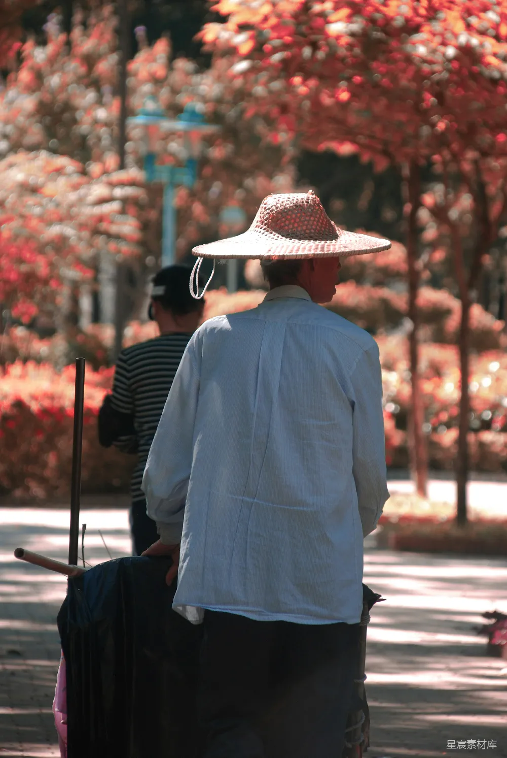 高清摄影 身穿蓝色衬衫、戴着棕色宽边帽的男人站在人行道上，白天拍摄