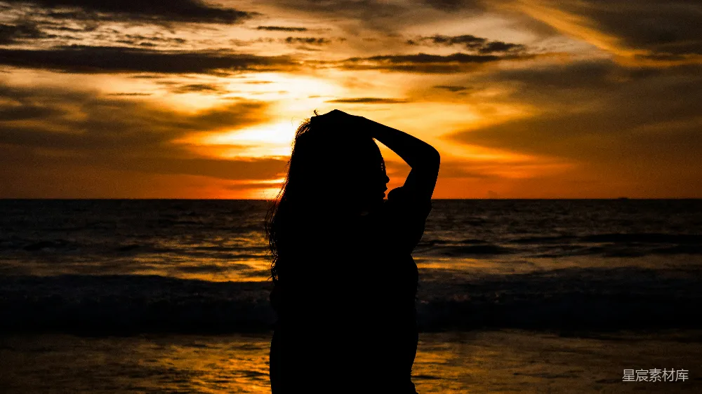高清摄影  夕阳下的海滩上站立着一名妇女