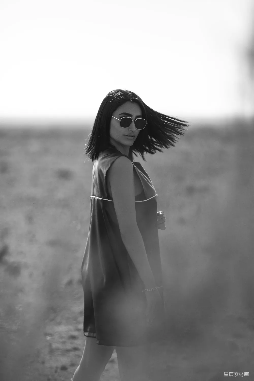 高清摄影 一个穿着连衣裙戴着太阳镜的女人在沙漠中行走