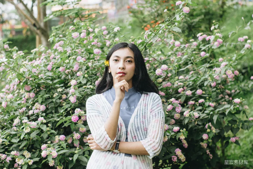 高清摄影 白灰条纹连衣裙的女人站在一旁的粉色花朵旁