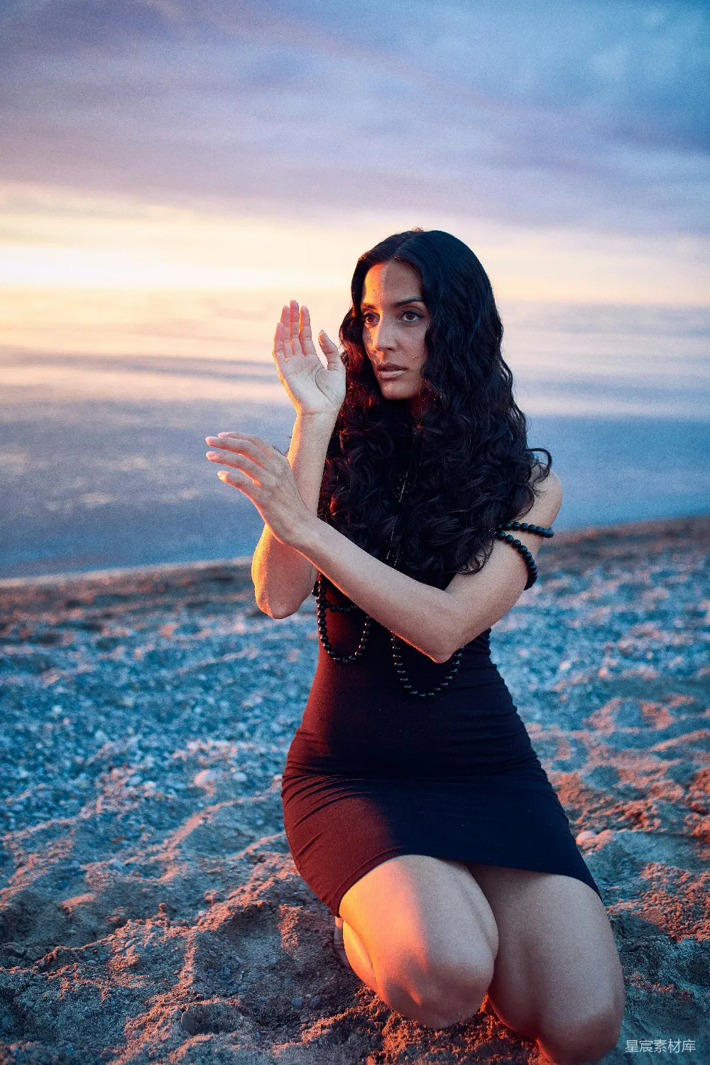 高清摄影  海滩上一位妇女跪着，双手合十。