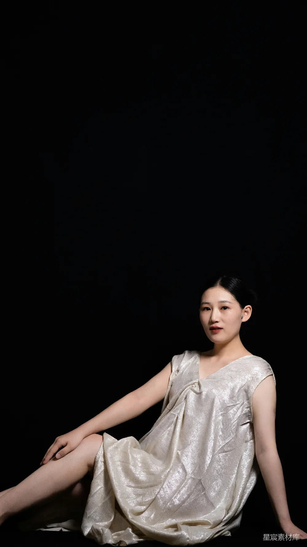 高清摄影  一个女人坐在地上穿着白色连衣裙。