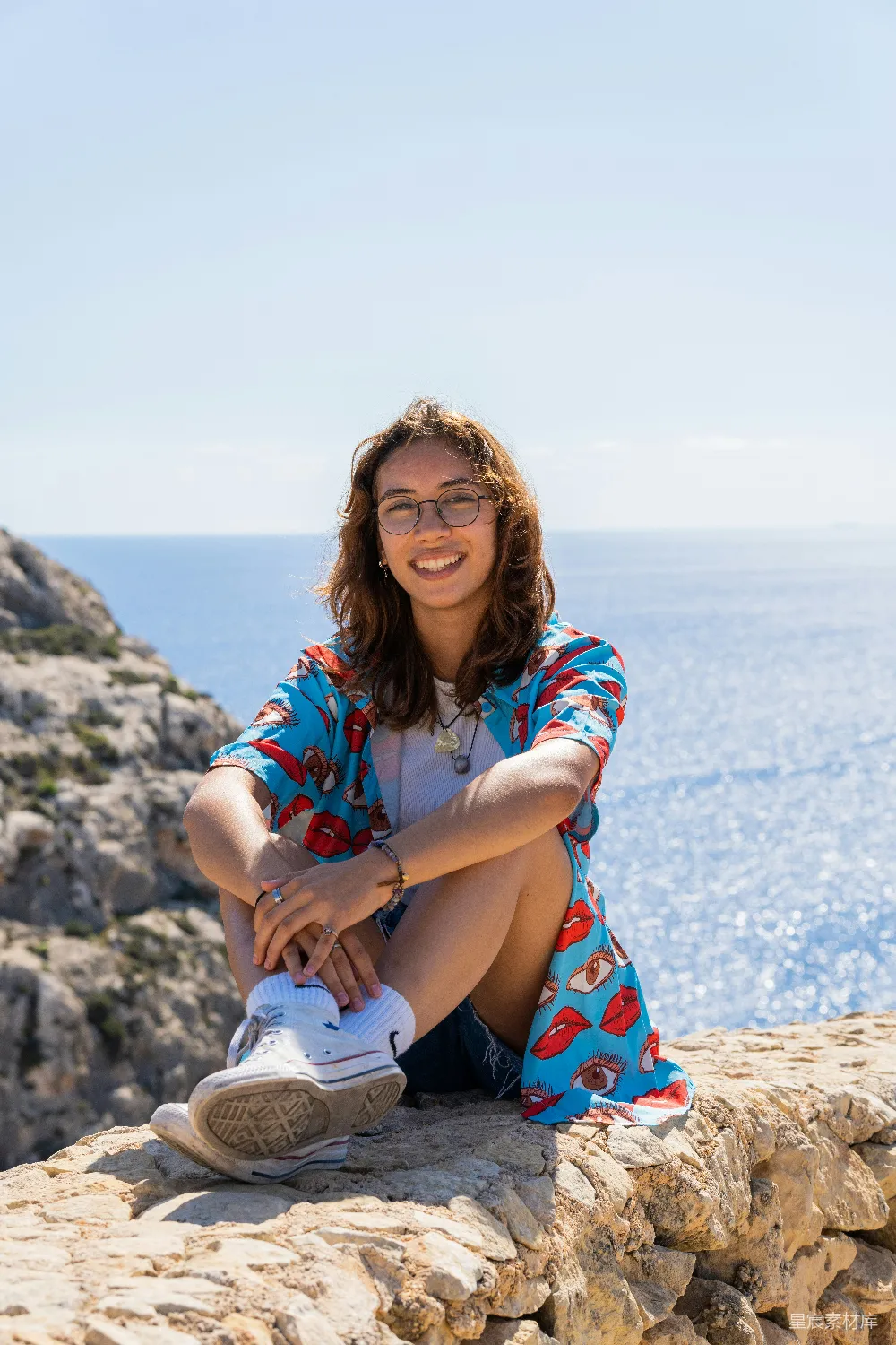 高清摄影 人物 旅行 一个女人坐在海边岩石上方。
