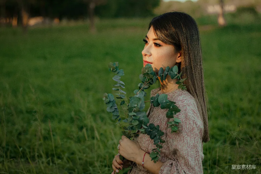 高清摄影  一个妇女站在田里拿着一株植物
