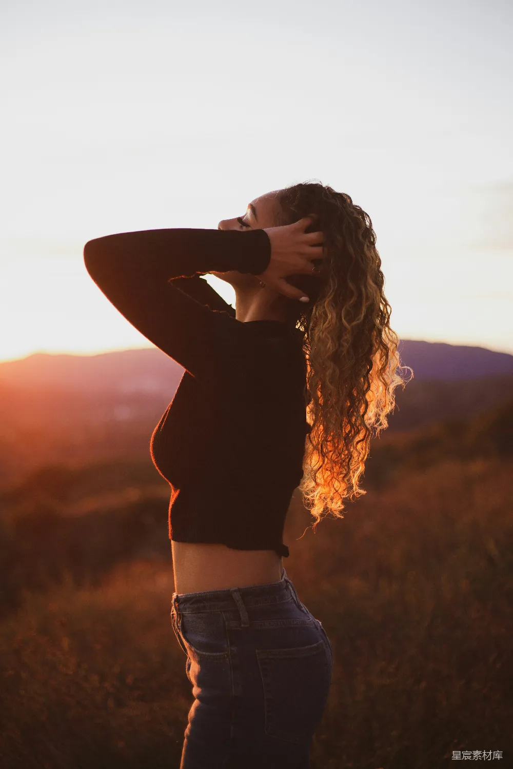高清摄影 妇女在白天站立时双手触摸着她的头发。