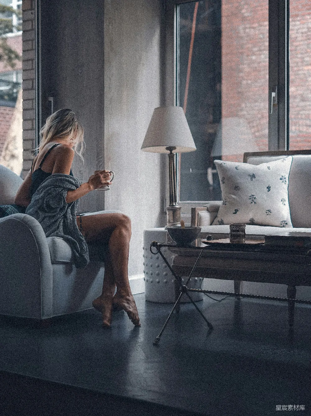 高清摄影  坐在灰色沙发椅上的女人拿着一个杯子。