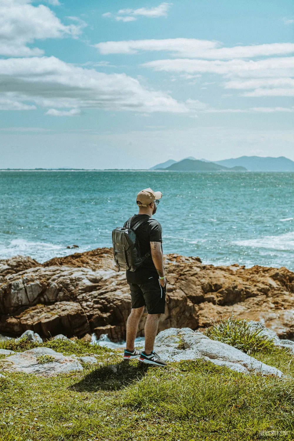 高清摄影  一个男人站在岩石上俯瞰着海洋。