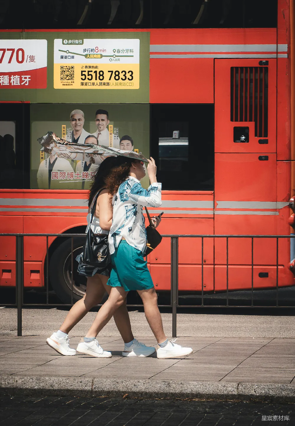 高清摄影  两个人走过一辆红色的双层巴士。