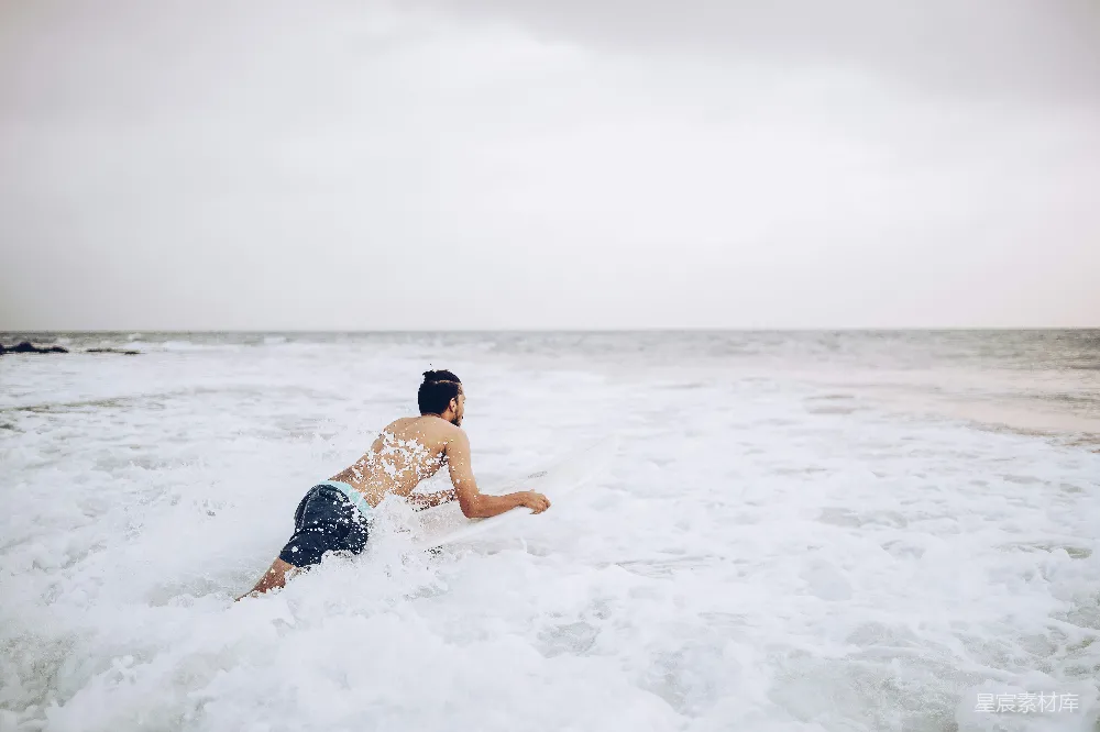 高清摄影  一个男子站在冲浪板上滑行在海浪上