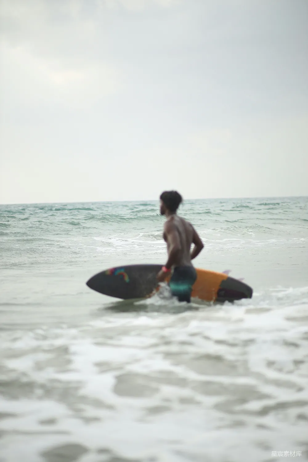高清摄影  一个男子站在海边拿着冲浪板。