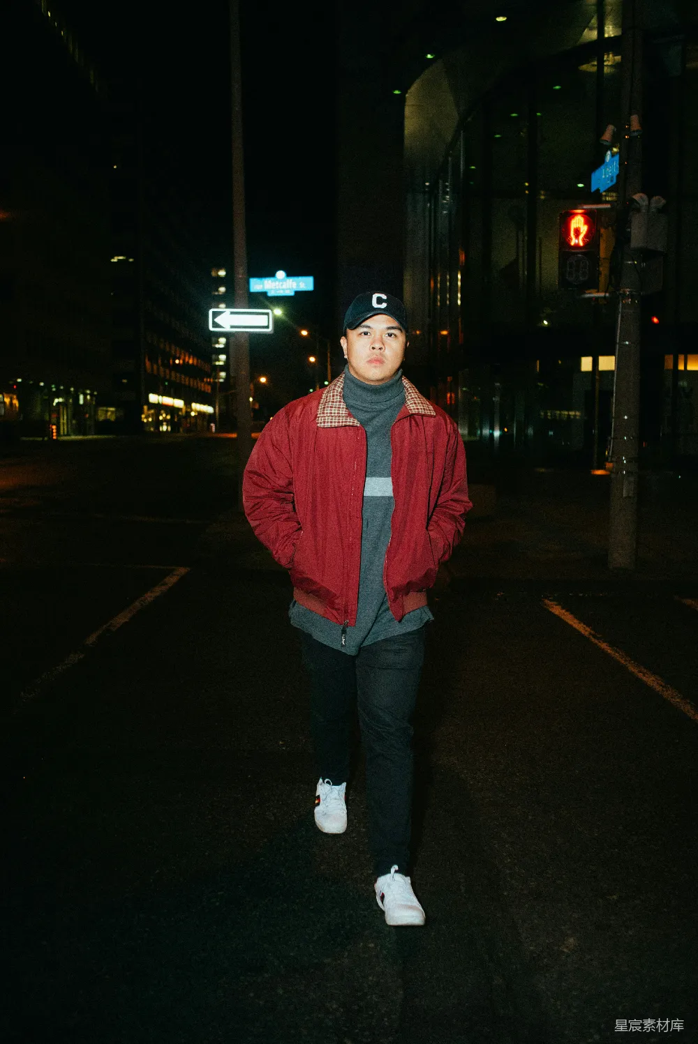 高清摄影  红衣男子站在 sidewalk 上，夜间的景象。