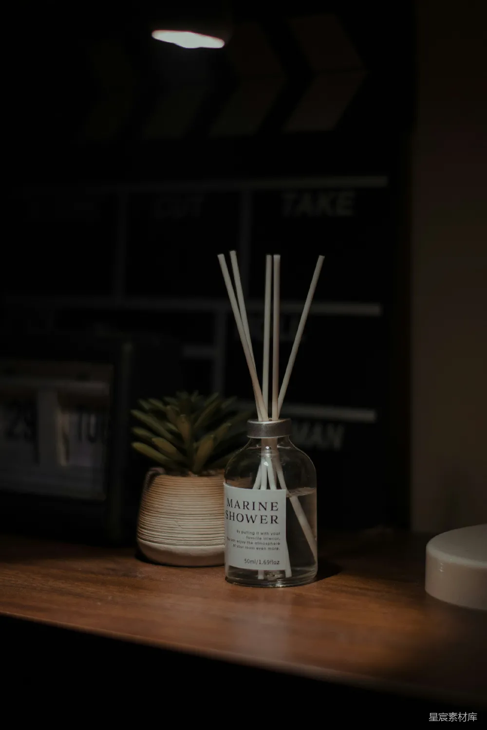 高清摄影  一个玻璃瓶旁边放置着一根香草香薰，旁边有一株菠萝植物。